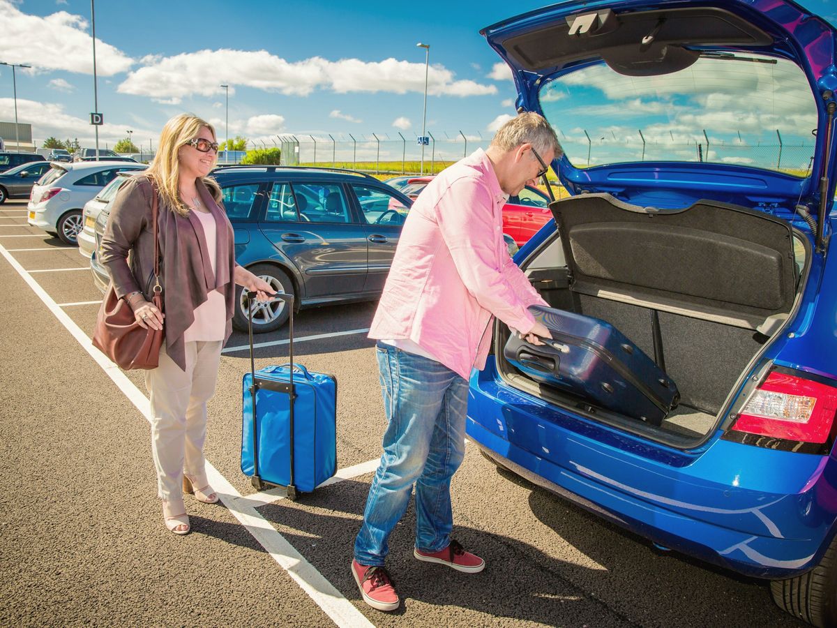 Duas amigas colocando malas no porta-malas de um carro